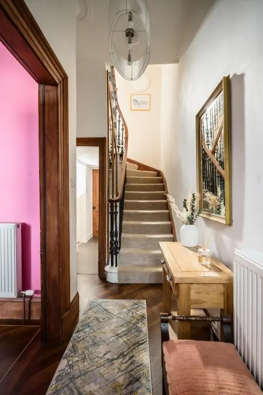 a hallway with a staircase with a wooden table and a stair case at Crown Jewel - Inverness City Centre in Inverness