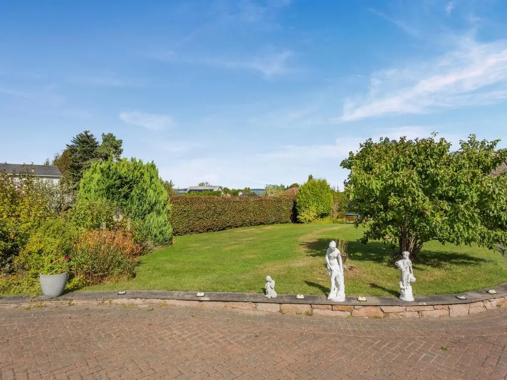 a garden with three statues in the middle of a yard at Charlies Cottage in Inverness