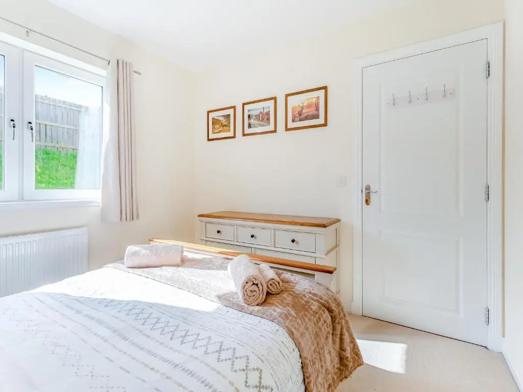 a white bedroom with a bed and a window at Kincraig Apartment in Inverness