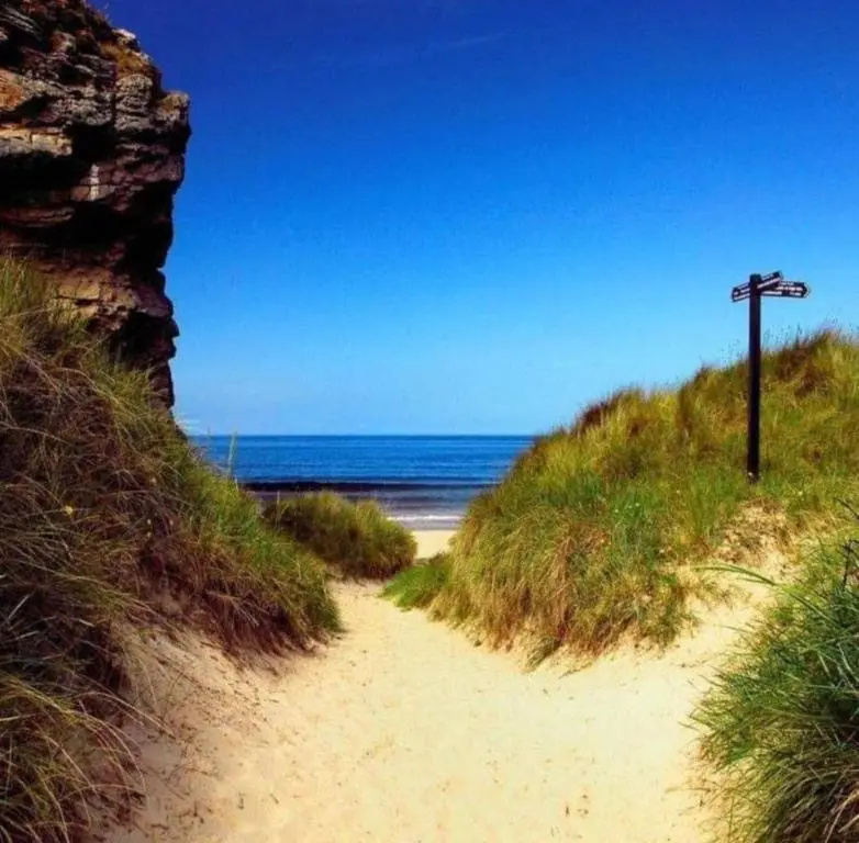 a sandy path leading to the ocean on a beach at Spacious Modern Seaside Caravan in Lossiemouth