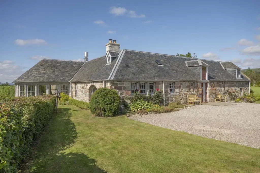 an old stone house with a garden in front of it at Drum Lodge in Nethy Bridge