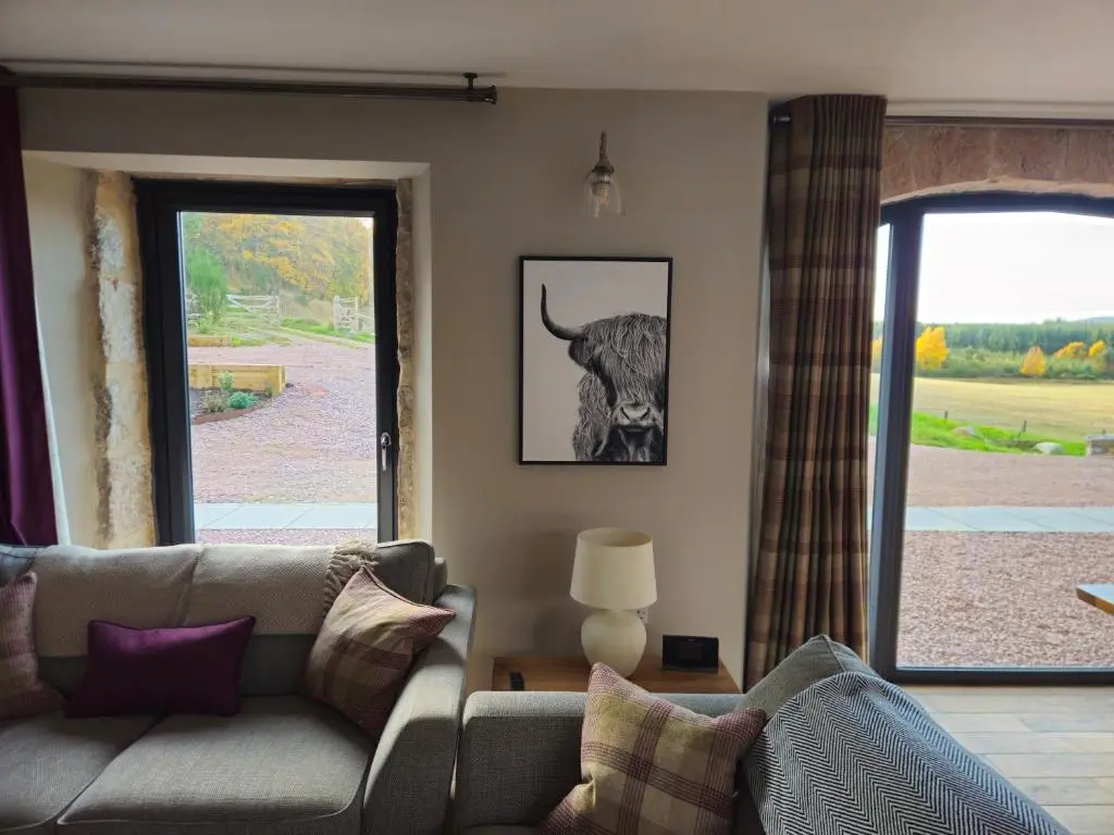 a living room with a couch and a window at Remore Steading - Coachhouse in Ardclach
