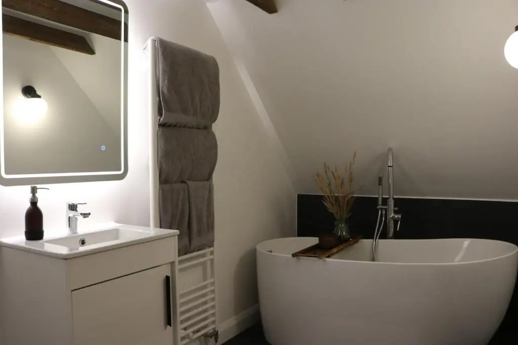 a bathroom with a white tub and a sink at Remore Steading - Coachhouse in Ardclach