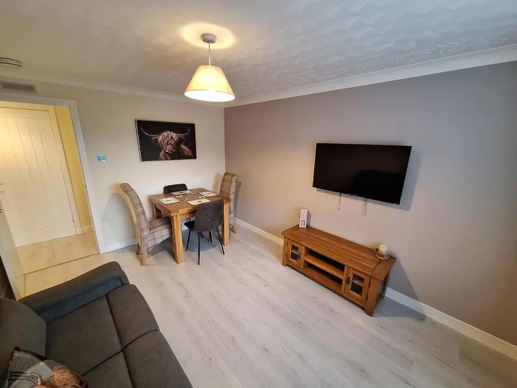 a living room with a table and a flat screen tv at Modern Two Bed City Apartment!! in Inverness