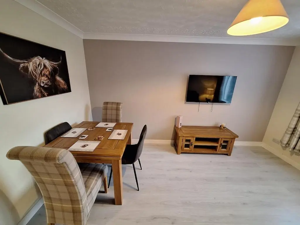 a dining room with a wooden table and a television at Modern Two Bed City Apartment!! in Inverness