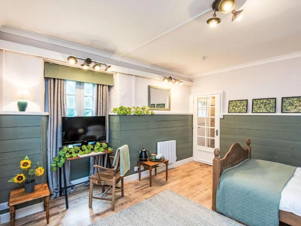a bedroom with a bed and a tv in a room at Holiday Home Highland Garden Room by Interhome in Drumnadrochit