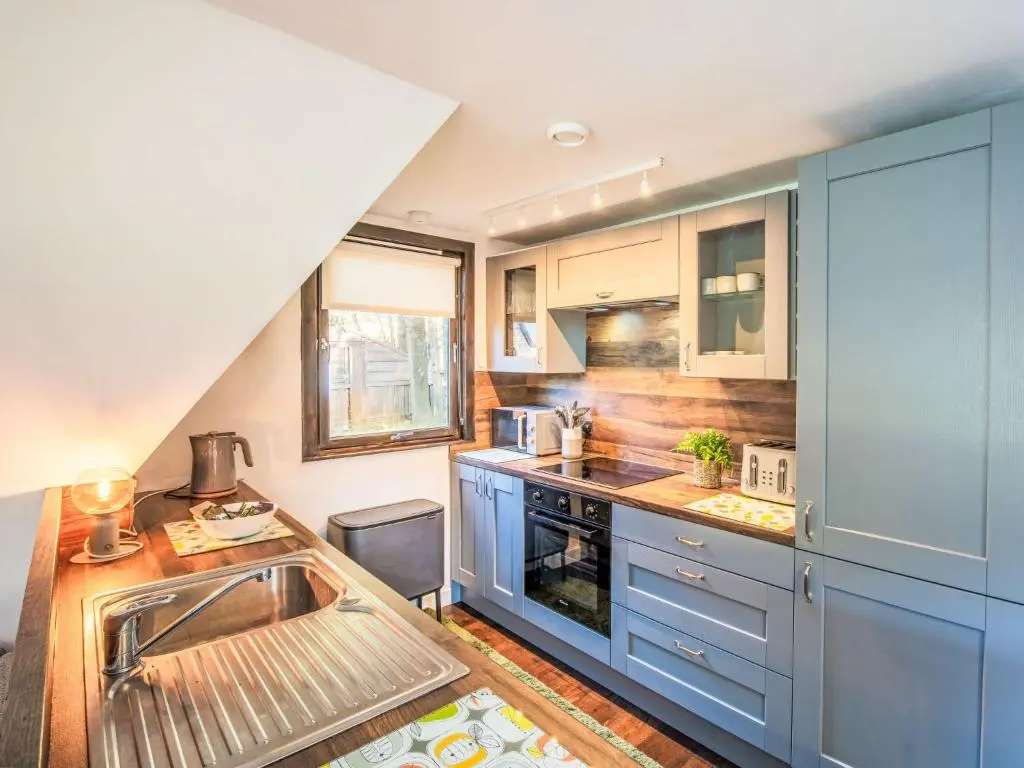 a kitchen with blue cabinets and a sink at Chalet Pine Needle Lodge by Interhome in Spean Bridge