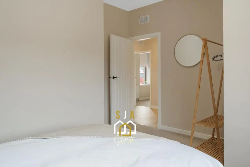 a bedroom with a bed and a mirror at Fraserburgh Residence - SJA Stays - Modern 3 Bed Apartment in Fraserburgh