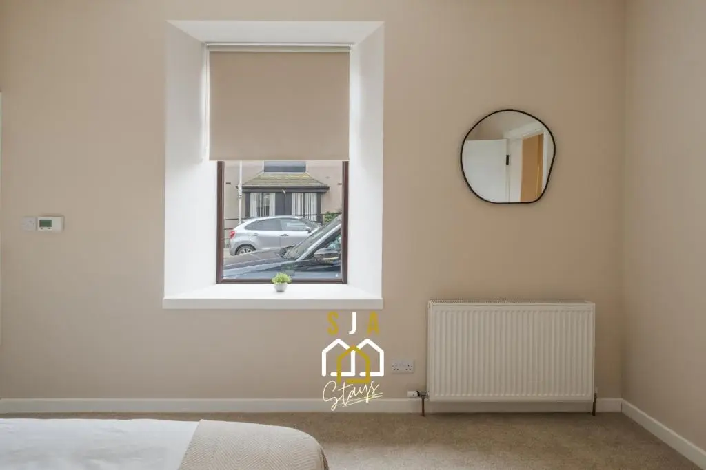 a bedroom with a window and a mirror at Fraserburgh Residence - SJA Stays - Modern 3 Bed Apartment in Fraserburgh