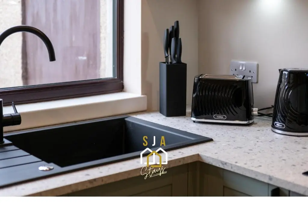 a kitchen counter with a black sink and a window at Fraserburgh Residence - SJA Stays - Modern 3 Bed Apartment in Fraserburgh