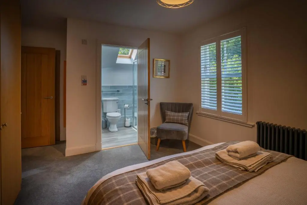 a bedroom with a bed and a chair and a window at Glen Tilt House in Bridge of Tilt