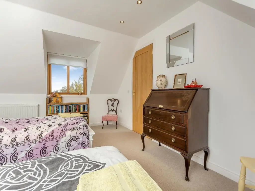 a bedroom with a bed and a dresser with a mirror at East Cottage in Cawdor