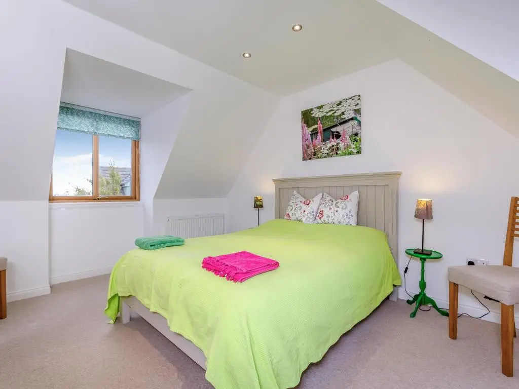 a bedroom with a green bed and a window at East Cottage in Cawdor