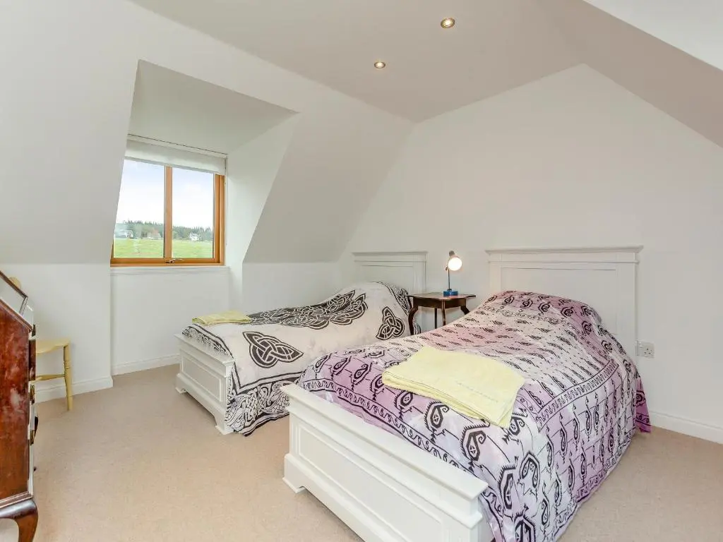 a white bedroom with two beds and a window at East Cottage in Cawdor