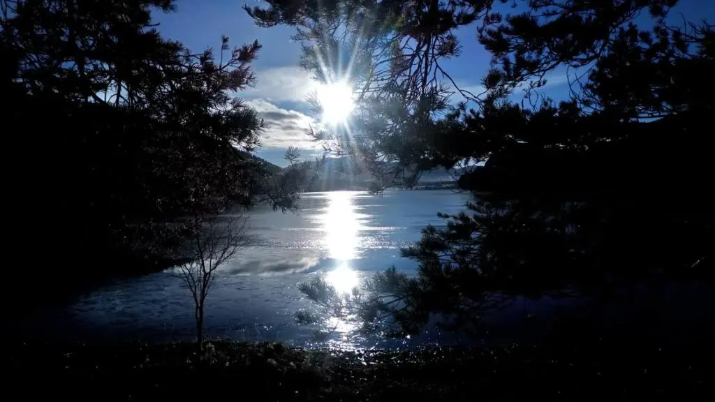 a sun shining over a river with snow on it at The Rowan in Boat of Garten