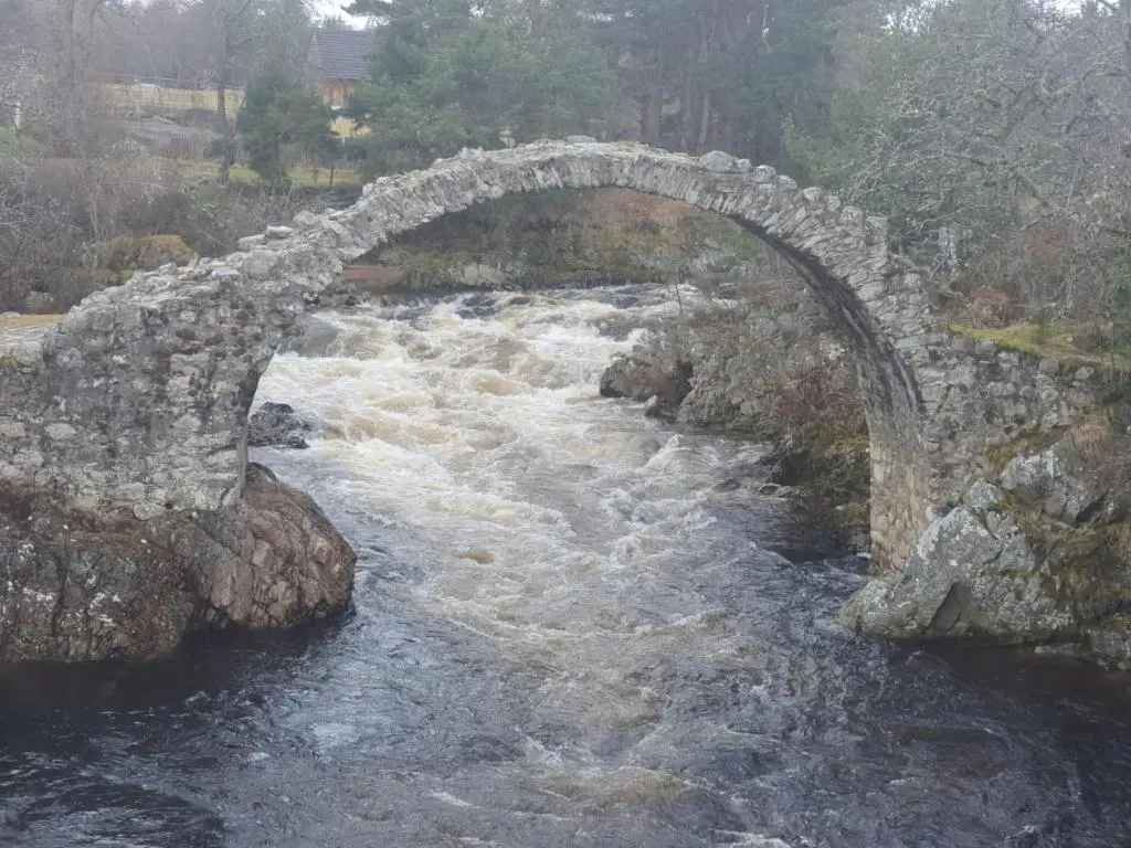 an old stone bridge over a rushing river at The Rowan in Boat of Garten