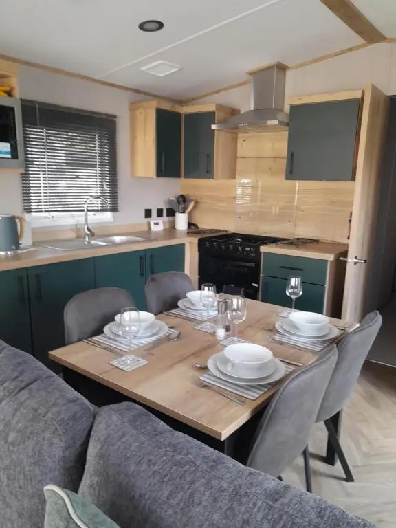 a kitchen with a wooden table with plates and wine glasses at The Rowan in Boat of Garten