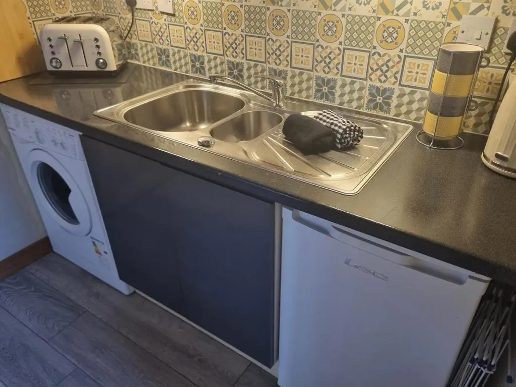 a kitchen counter with a sink and a dishwasher at Village view apartment in Auldearn