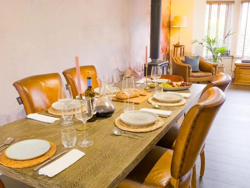 a wooden table with plates and wine glasses on it at 18 Dalfaber Park- with hot tub in Aviemore in Aviemore