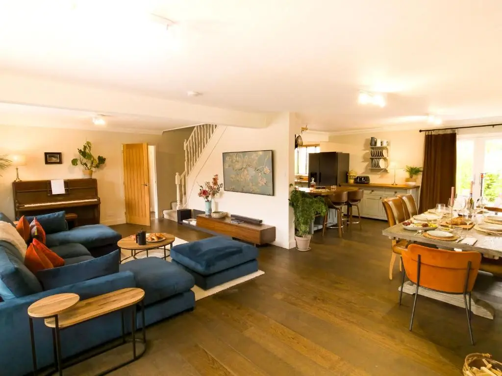 a living room with a blue couch and a table at 18 Dalfaber Park- with hot tub in Aviemore in Aviemore