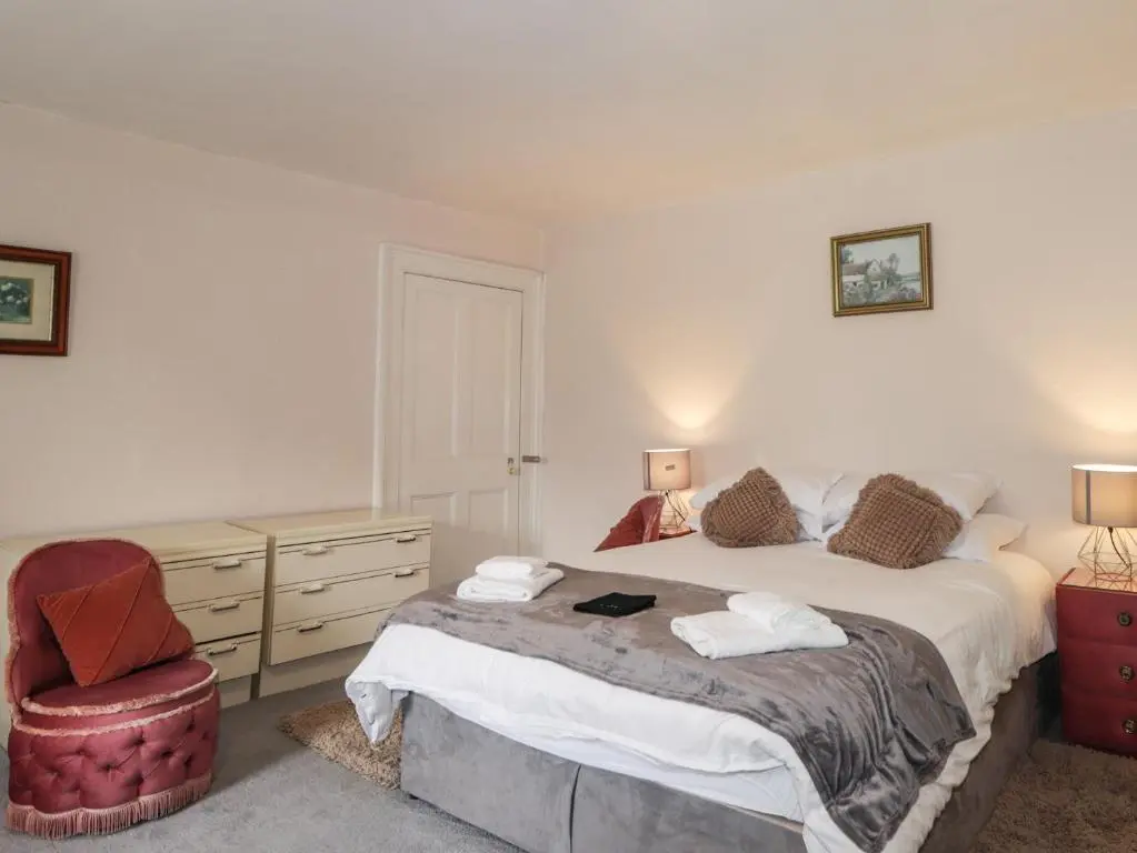a bedroom with a large bed and a chair at Ivy House in Kingussie