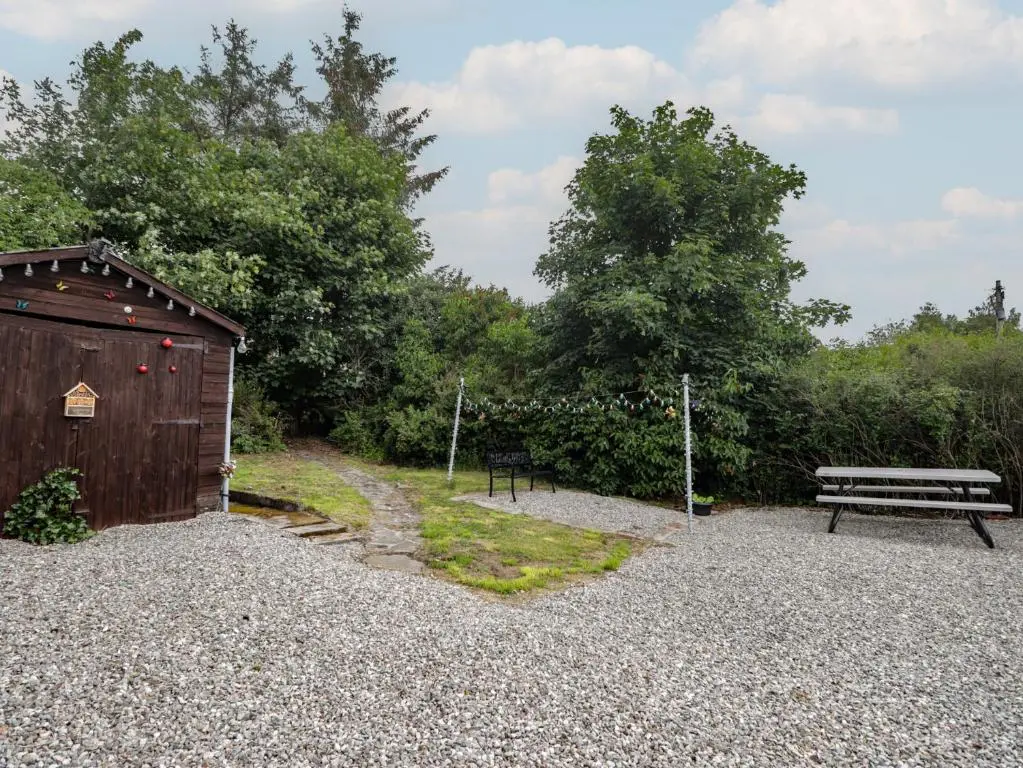 a bench sitting next to a wooden shed with a park at Ivy House in Kingussie