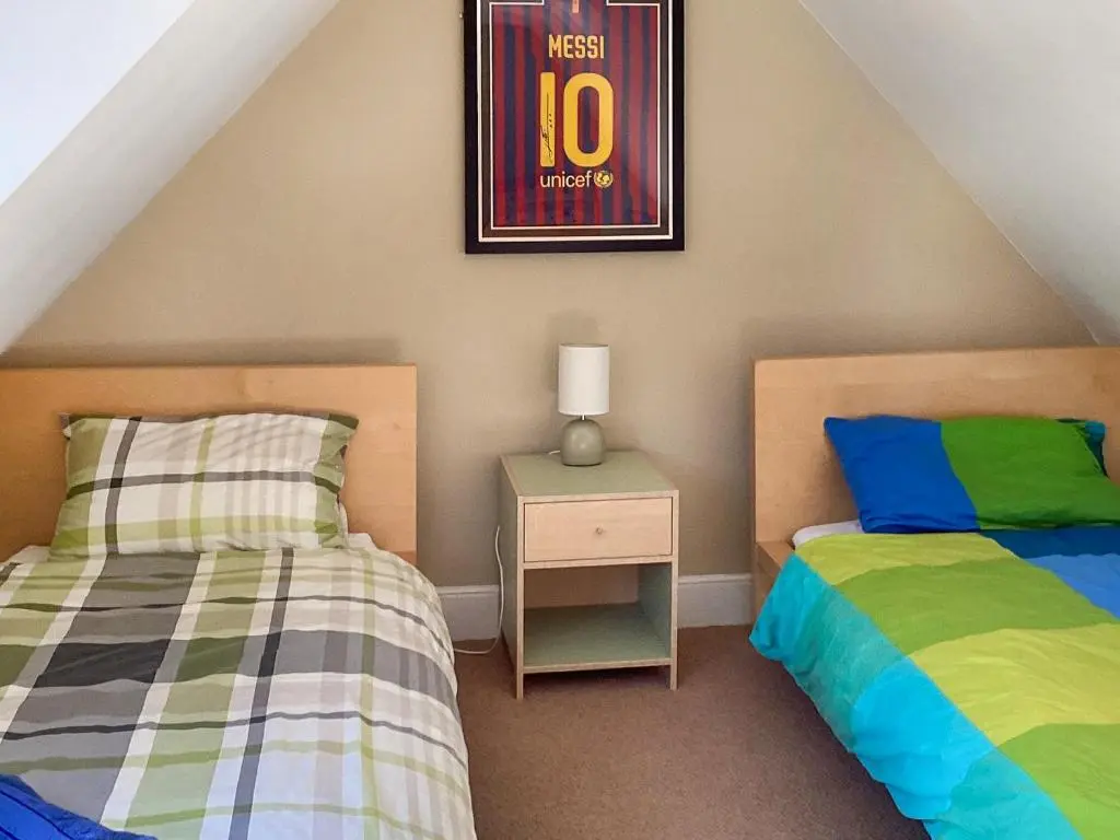 a bedroom with two beds and a picture on the wall at Old Laurel Cottage in Jemimaville