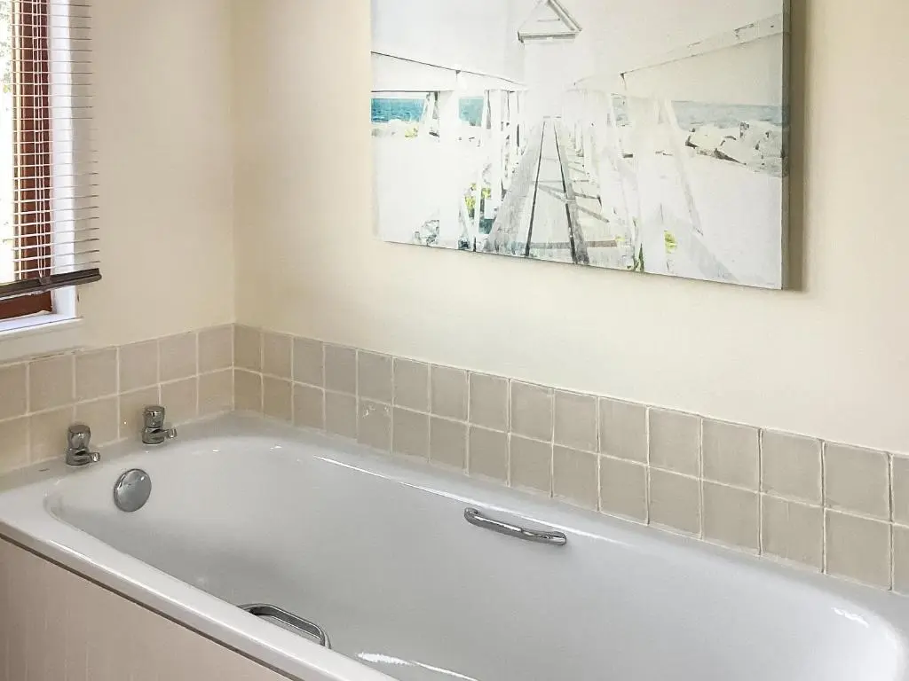 a bath tub in a bathroom with a picture on the wall at Old Laurel Cottage in Jemimaville