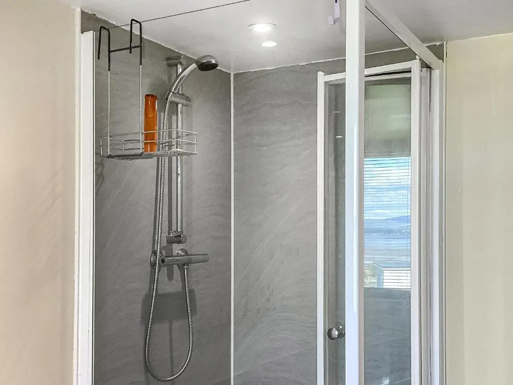 a shower in a bathroom with a glass door at Old Laurel Cottage in Jemimaville