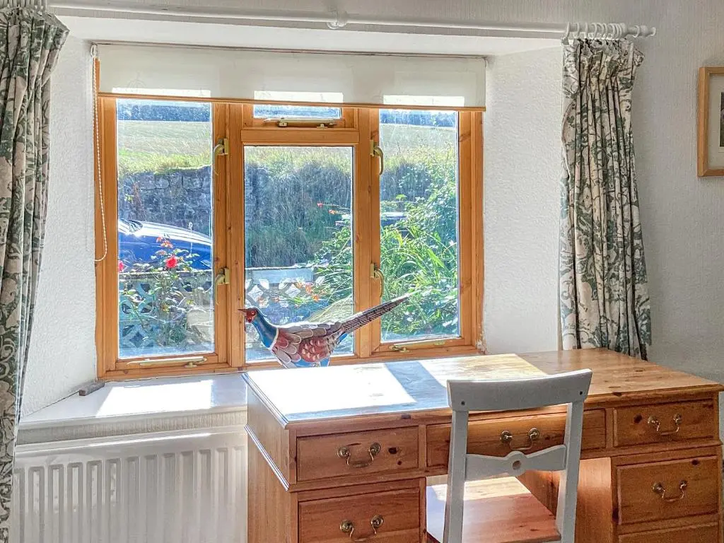 a desk with a window with a bird on it at Old Laurel Cottage in Jemimaville
