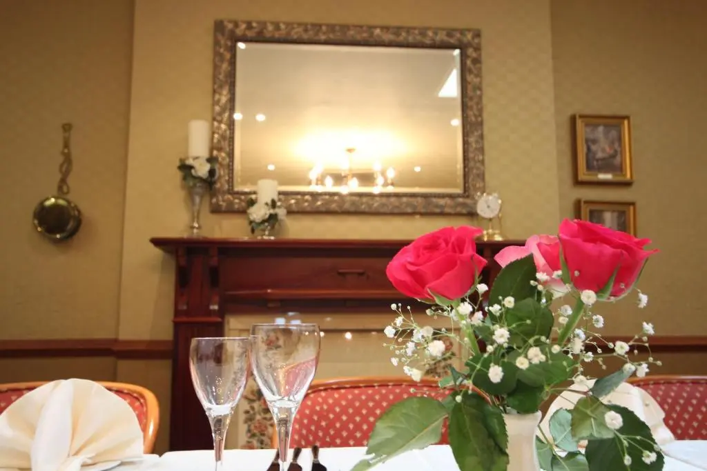 a table with a vase of roses and a mirror at Strathburn Hotel Inverurie by Compass Hospitality in Inverurie