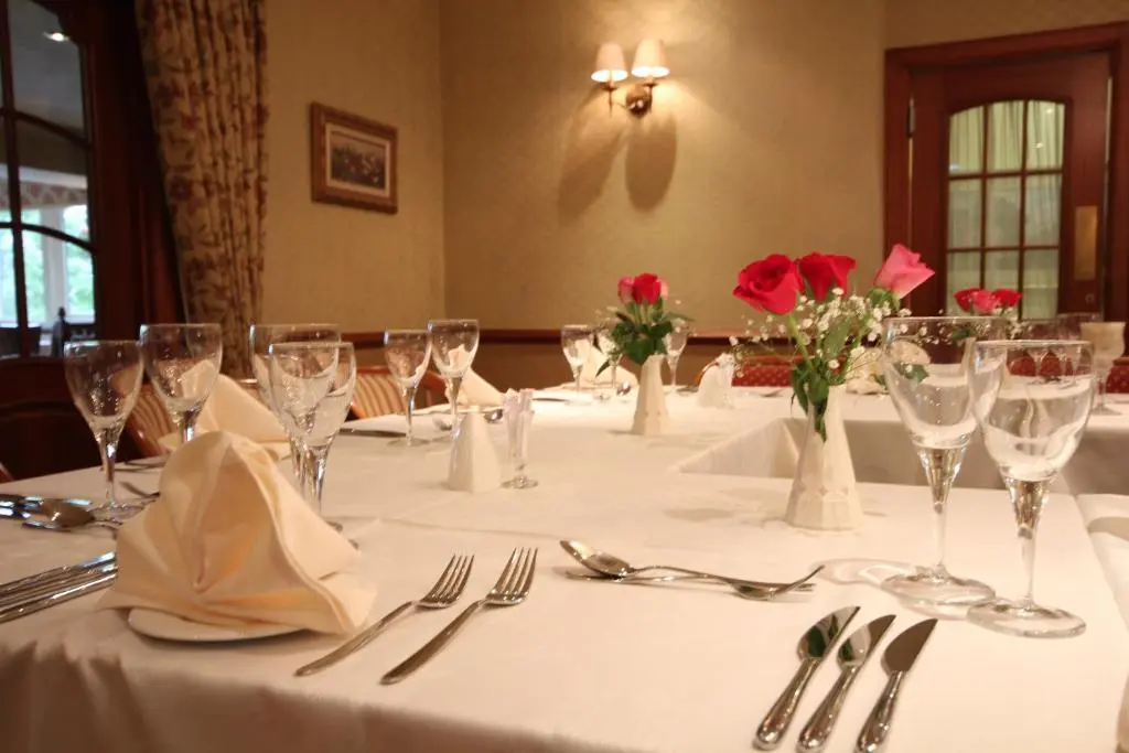 a table with wine glasses and red roses on it at Strathburn Hotel Inverurie by Compass Hospitality in Inverurie