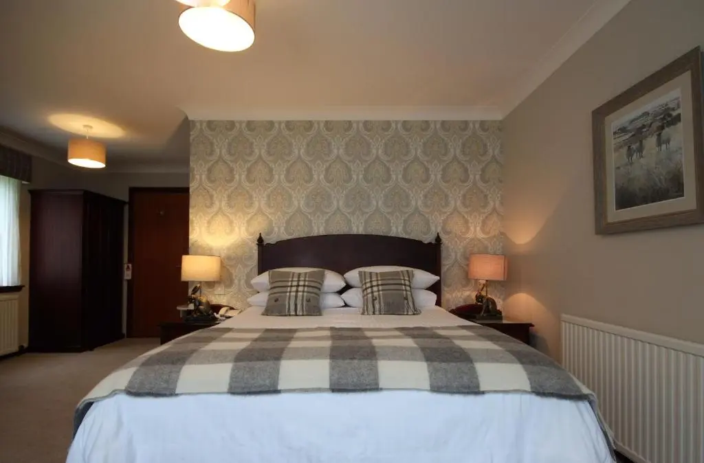 a bedroom with a large bed with two lamps at Strathburn Hotel Inverurie by Compass Hospitality in Inverurie