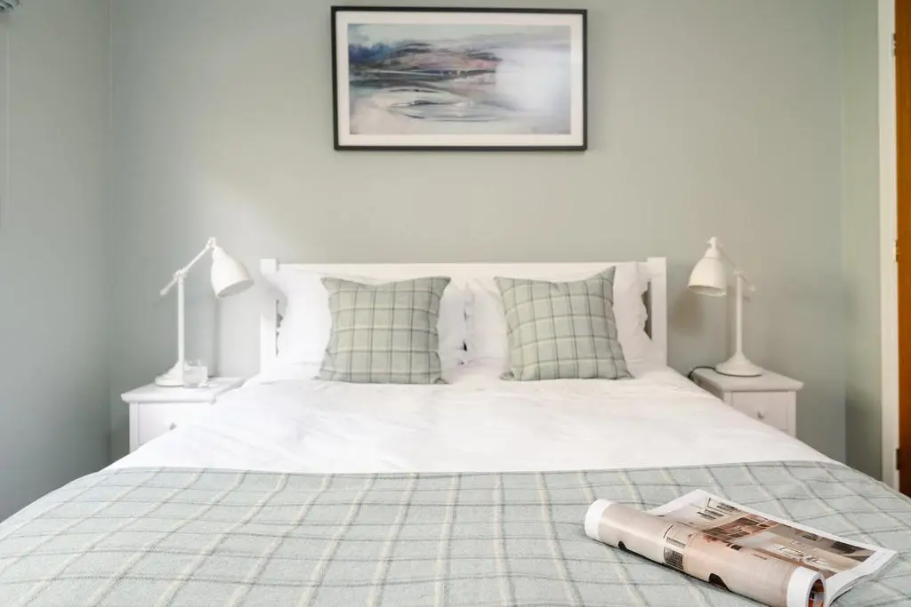 a bedroom with a white bed with a book on it at Kintail - Seasgair Lodges in Inverdruie