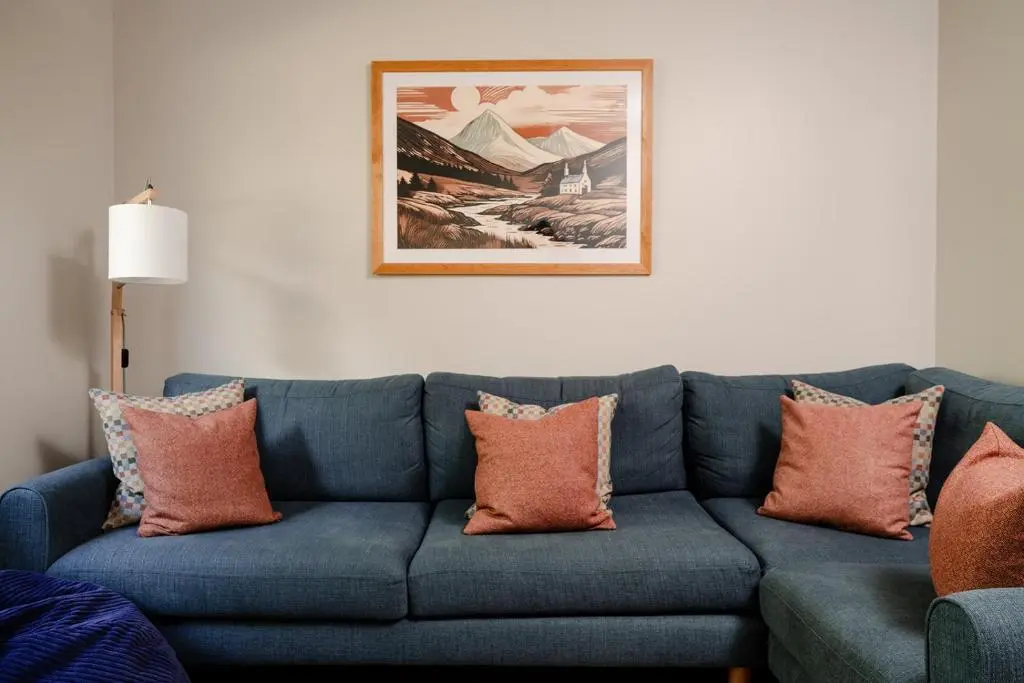 a blue couch with orange pillows in a living room at Kintail - Seasgair Lodges in Inverdruie