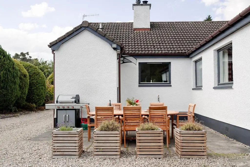 a patio with chairs and a grill in front of a house at Kintail - Seasgair Lodges in Inverdruie