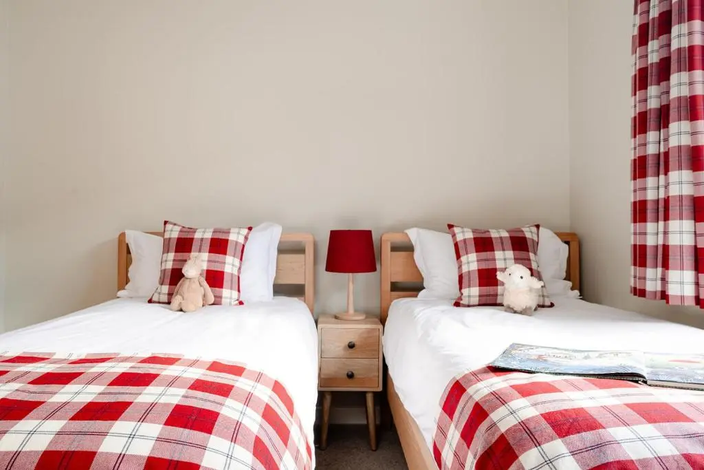 two beds with teddy bears sitting on them in a bedroom at Kintail - Seasgair Lodges in Inverdruie