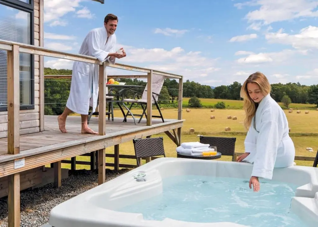 a man and woman in a bath tub on a deck at Kessock Highland Lodges in Tore