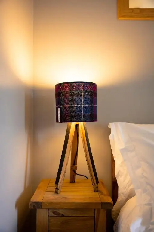 a lamp on a table next to a bed at Wynstone Cottage, Speyside in Fochabers