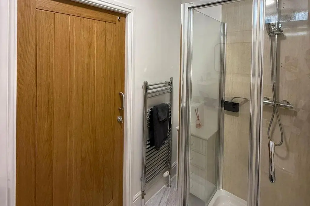 a bathroom with a shower and a wooden door at 1 Bed Flat - Sleeps 2 - Parking - Wifi in Nairn