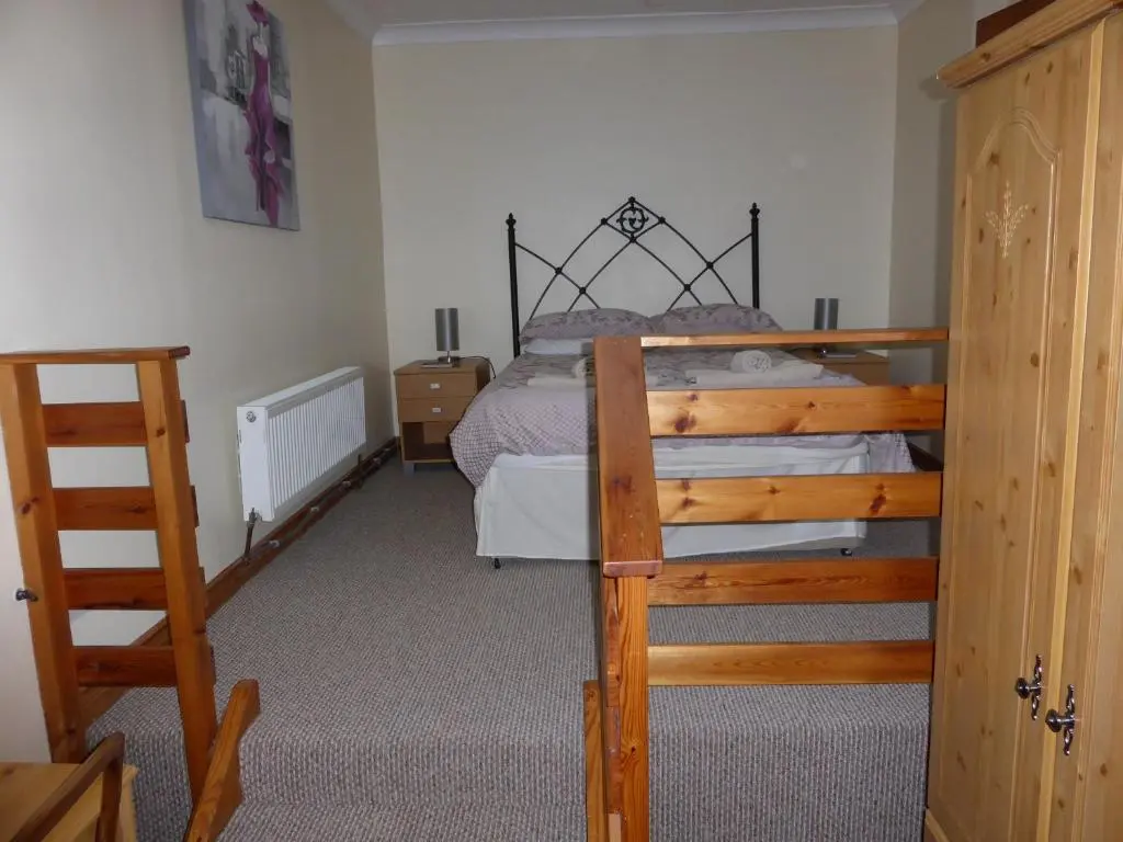 a bedroom with a bed with a wooden frame at Treetops Bungalow Loch Ness in Drumnadrochit