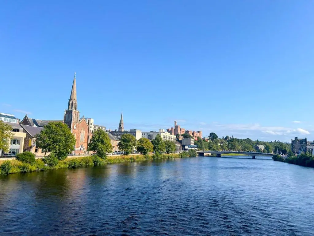 a river in a city with a bridge and buildings at King Cosy 2 Bedroom Apartment - Inverness in Inverness