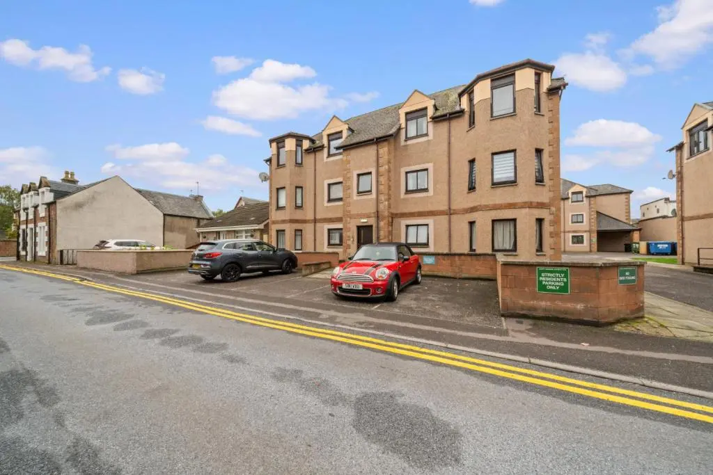 two cars parked in a parking lot in front of a building at King Cosy 2 Bedroom Apartment - Inverness in Inverness