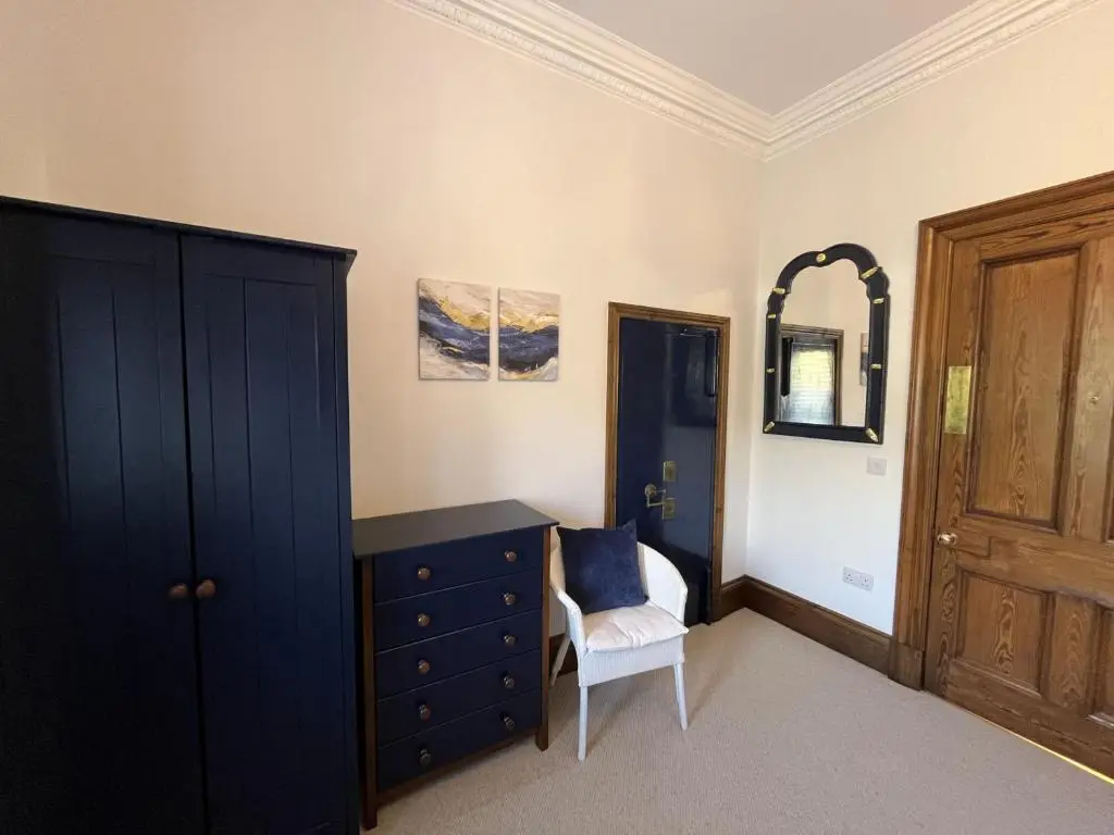 a bedroom with a blue dresser and a chair at Bank House apartment in Fort Augustus