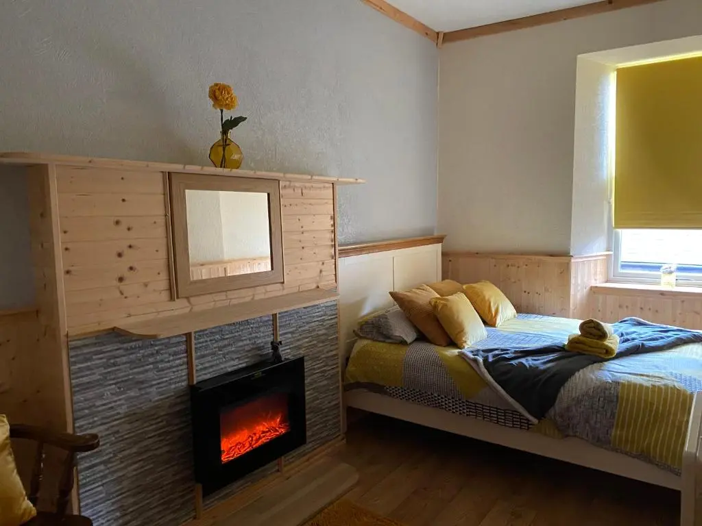 a bedroom with a bed and a fireplace at Georges holiday apt the blue suite in Inverness