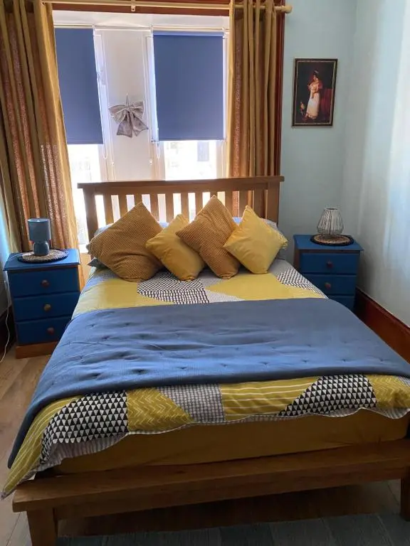a bed with blue and yellow sheets and pillows at Georges holiday apt the blue suite in Inverness