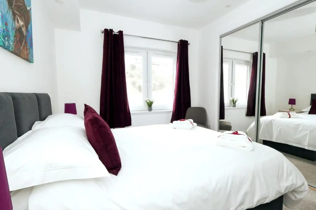 a bedroom with two beds and a mirror at Inverness Haven: Bright 2B/2B with Scenic Views in Inverness