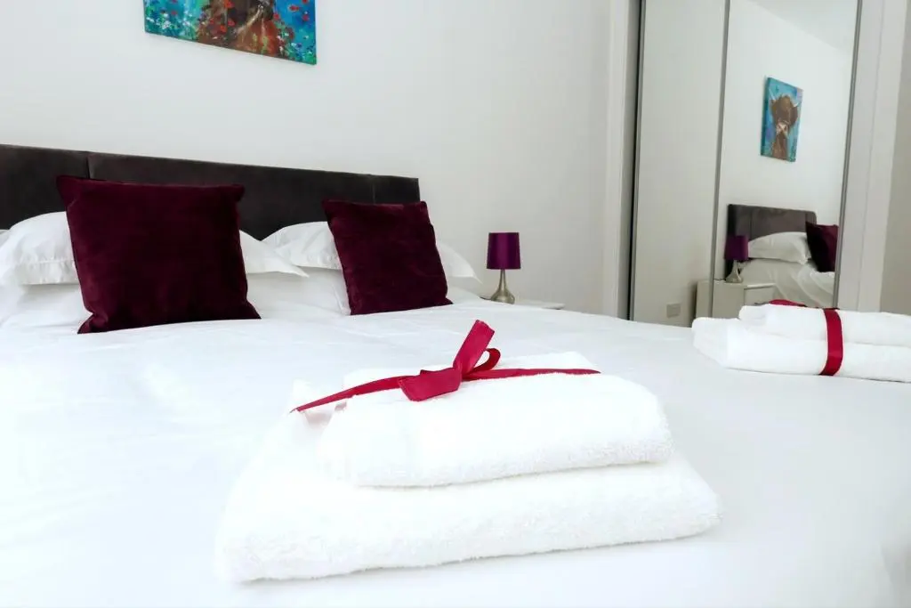 a white bed with two towels on top of it at Inverness Haven: Bright 2B/2B with Scenic Views in Inverness