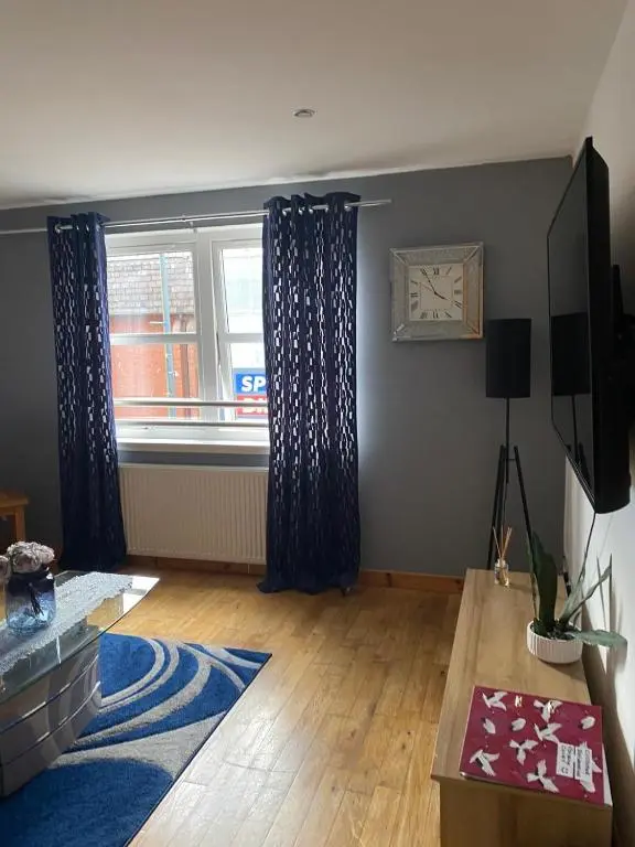 a living room with a large window with blue curtains at Georges 1Faraline court Apartment in Inverness