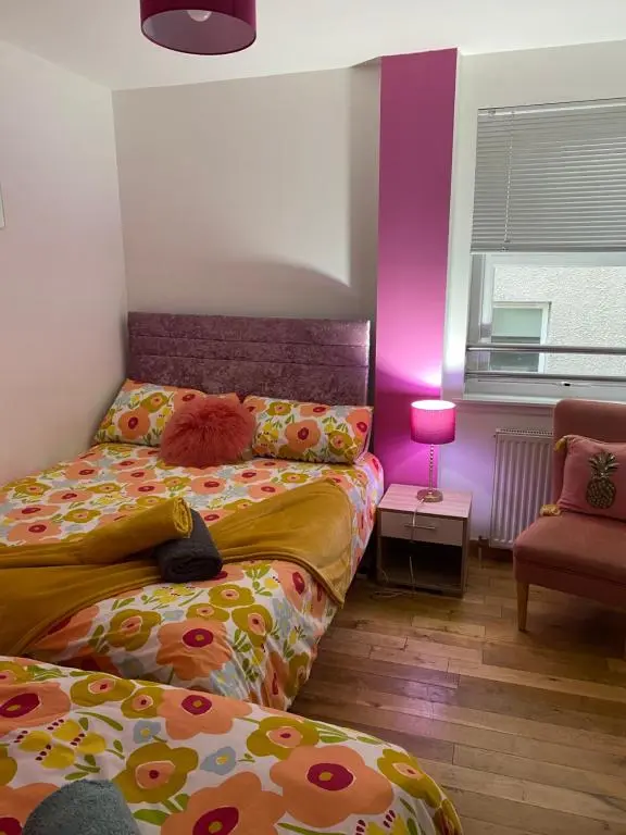 a bedroom with two beds and a pink lamp at Faraline in Inverness